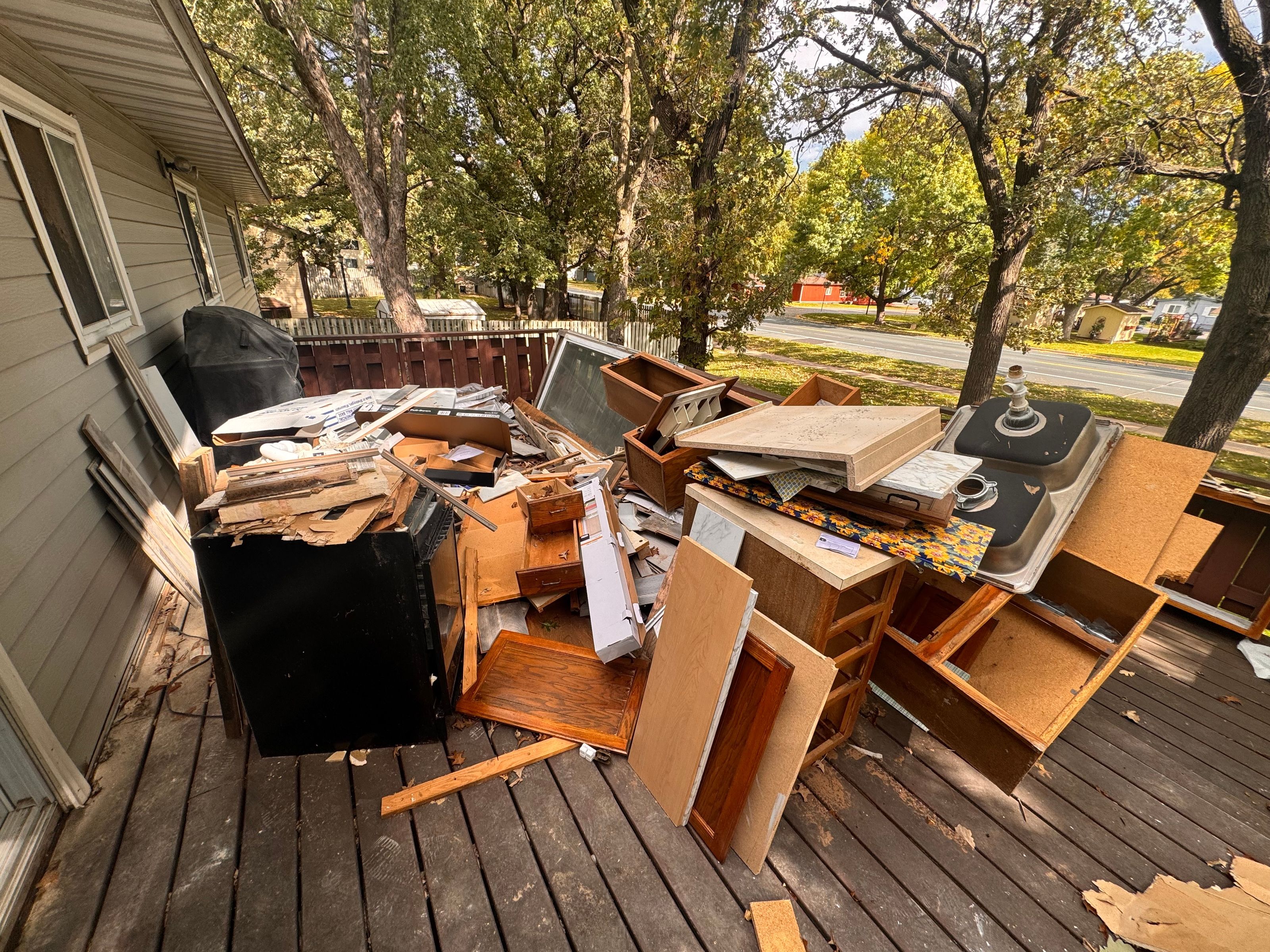 Torn-out kitchen cabinets and countertops piled on a deck for debris removal