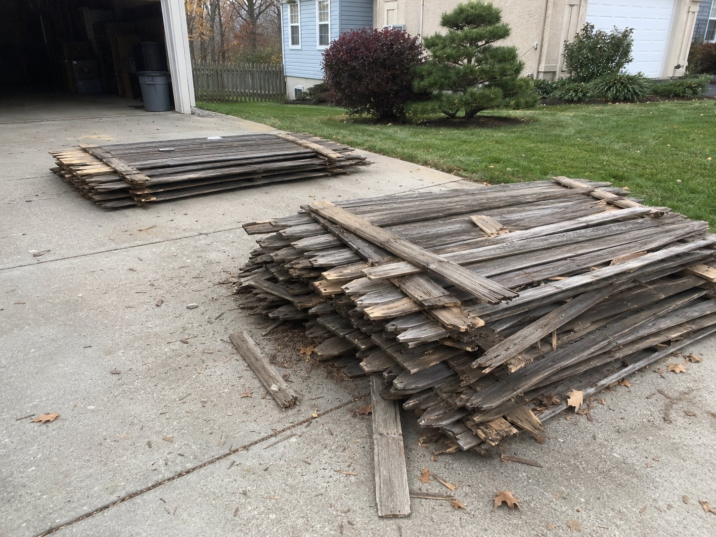 Torn-out fence pickets stacked in a yard